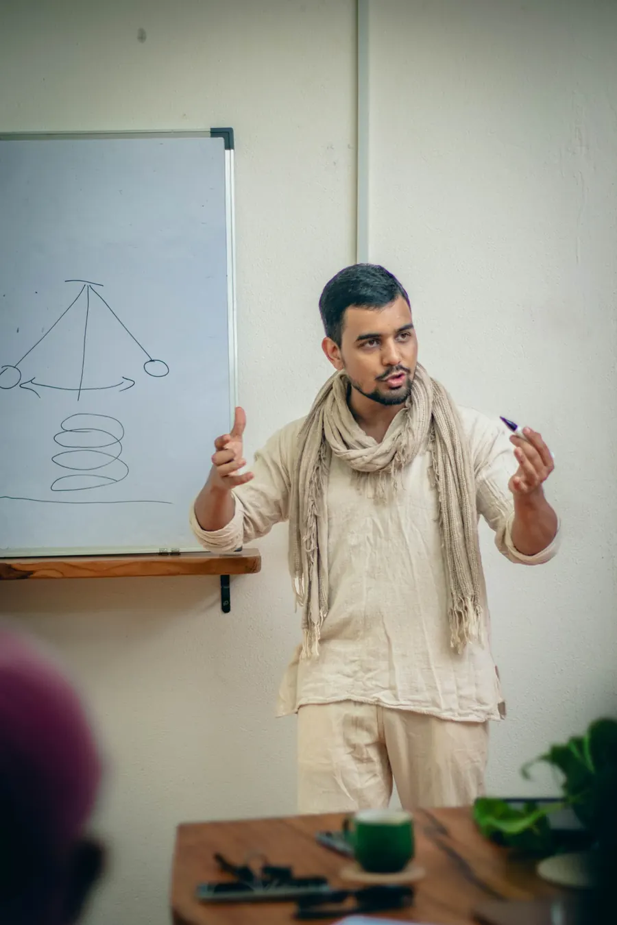 Himanshu Bisht teaching with a pendulum and spiral drawn on the whiteboard