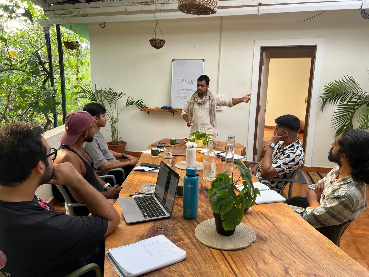Himanshu Bisht leading a workshop for founders seated around a long wooden table